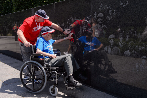 Honor Flight Veteran with Guardian next to American Flag