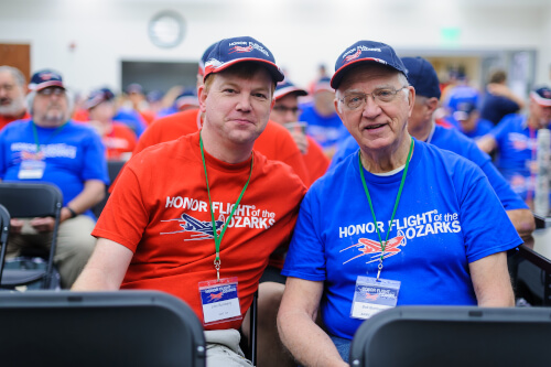 Honor Flight Veteran with Guardian next to American Flag