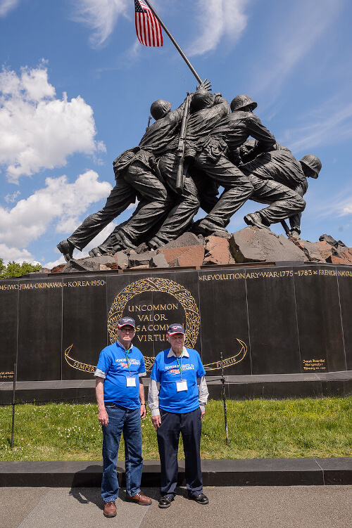 Honor Flight Veteran with Guardian next to American Flag