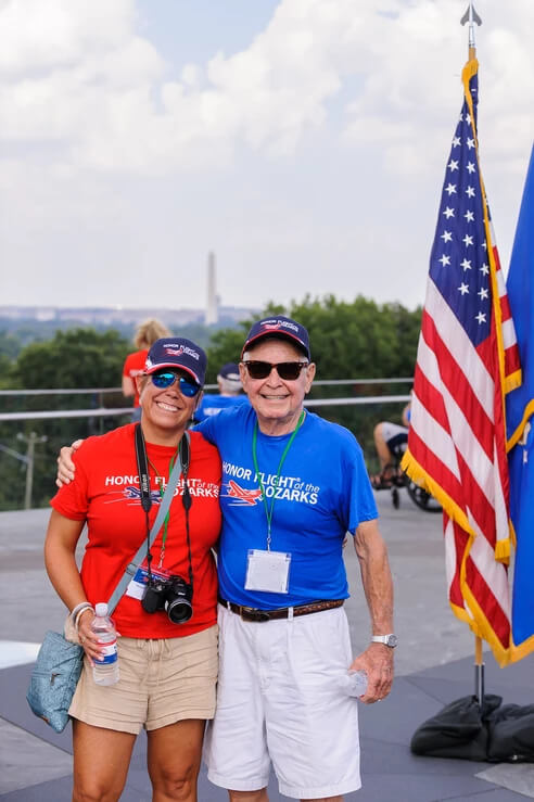 Honor Flight Veteran with Guardian next to American Flag